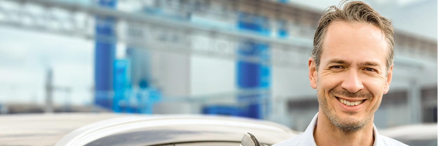 Mann steht lächelnd neben seiner Autotür und freut sich als Unternehmer über die massgechneiderten Mobilitätslösungen von Arval