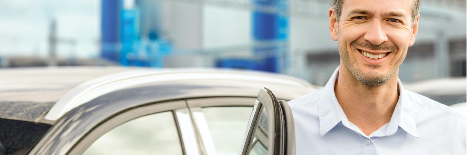 Arval Mobilität im Mittelstand-Mann neben Auto Mann steht lächelnd neben seiner Autotür und freut sich als Unternehmer über die massgechneiderten Mobilitätslösungen von Arval