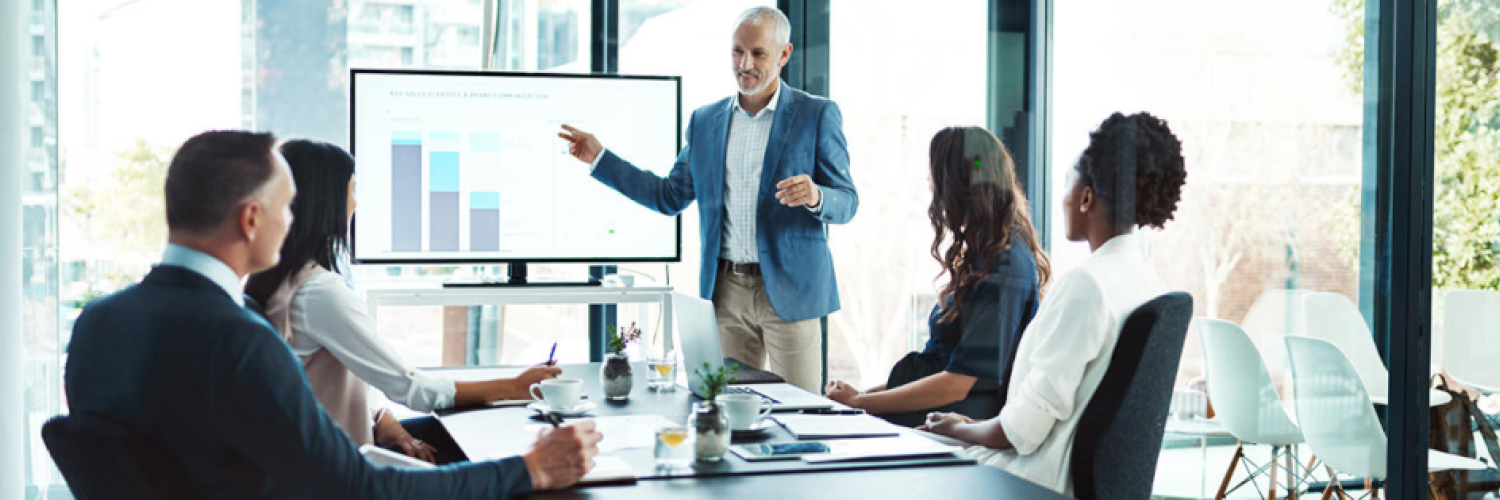 Mann erklärt Balkendiagramm im Zusammenhang mit der Beratungsmethodik Arval STAR am PC-Bildschirm während eines Meetings am Konferenztisch