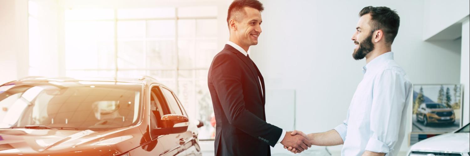 Arval Partnerschaften für sorgenfreien Mobilitätslösungen Zwei Männer in einem Autohaus geben sich die Hand als Zeichen einer Übereinkunft