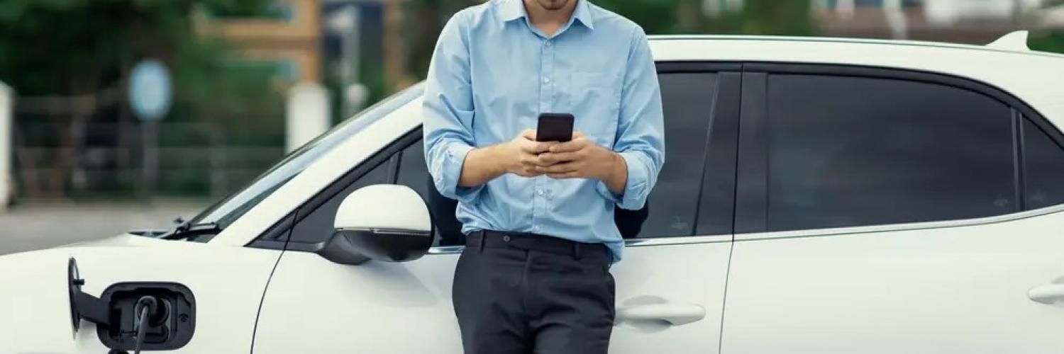 My arval-willkommen-mann mit handy vor auto Mann mit Handy in der Hand lehnt an weißem Auto und bedient die app my arval