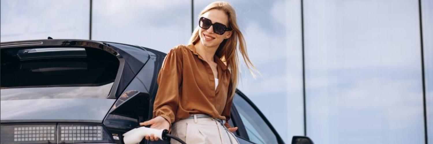 Frau beim Laden an einem Elektrofahrzeug gelehnt