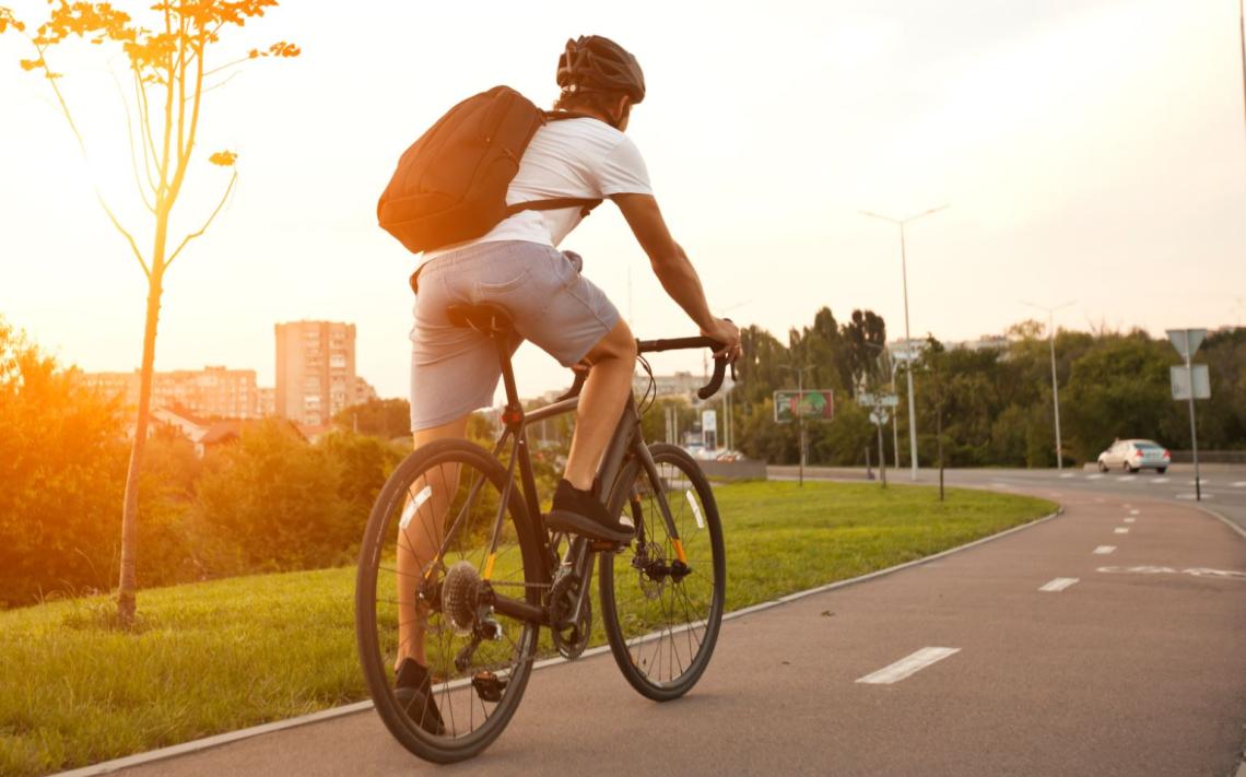 Arval Mittelstand-Bike Leasing-Biker zur Sunset Stimmung Sicht auf Fahrradfahrer von hinten auf einem Fahrradweg mit Sonnenuntergangstimmung der motiviert durch Bike Leasing von Arval nach Hause fährt