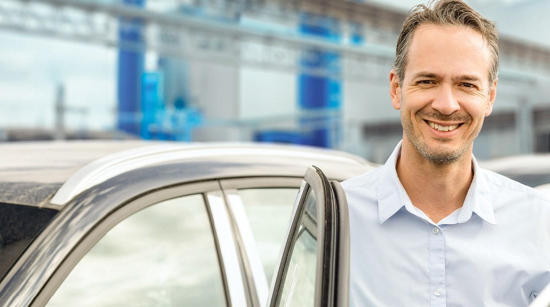 Mann lächelnd hinter seiner geöffneten Autotüre